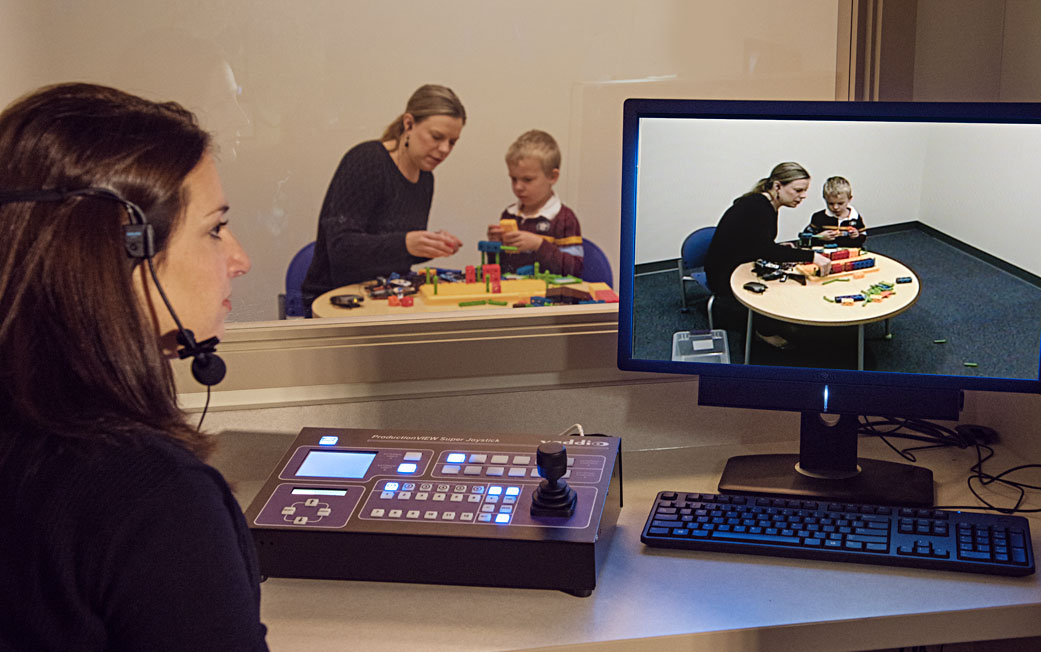 As parents interact with their children in an observation room, clinicians can offer guidance via an earpiece.